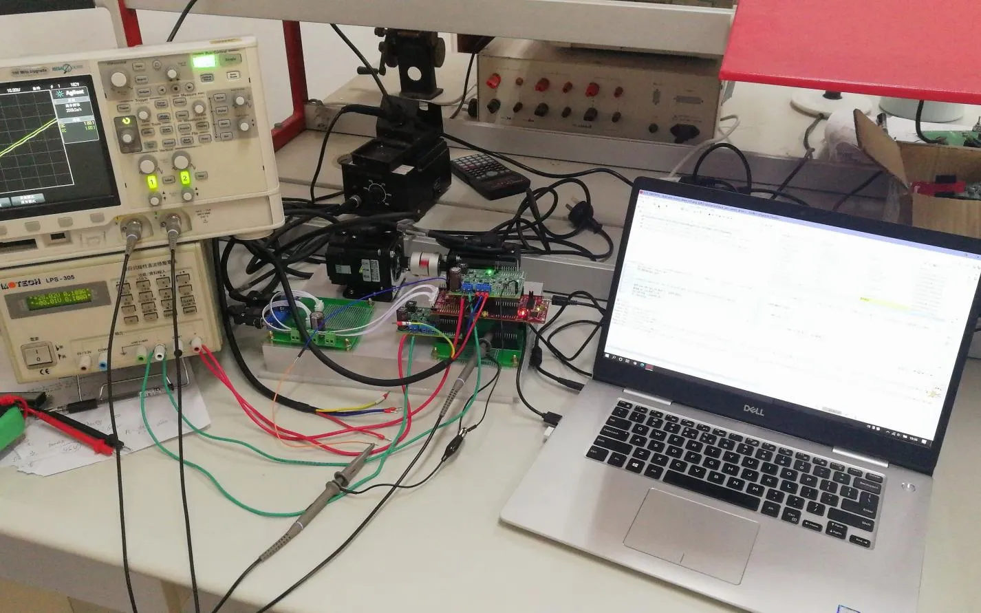 Prototype PCB validation and debugging setup with oscilloscope, power supply, test board and laptop